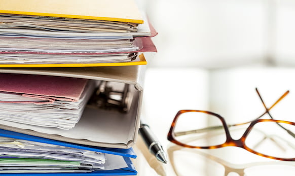 Stack of paper-filled binders on a desk