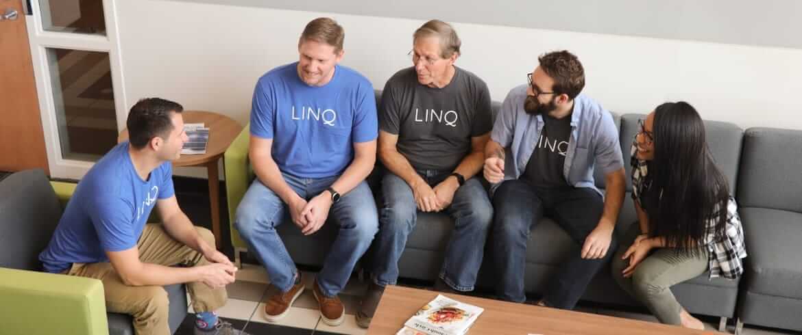 Members of the LINQ team sitting and chatting on the couch in the lobby in the Wilmington Headquarters