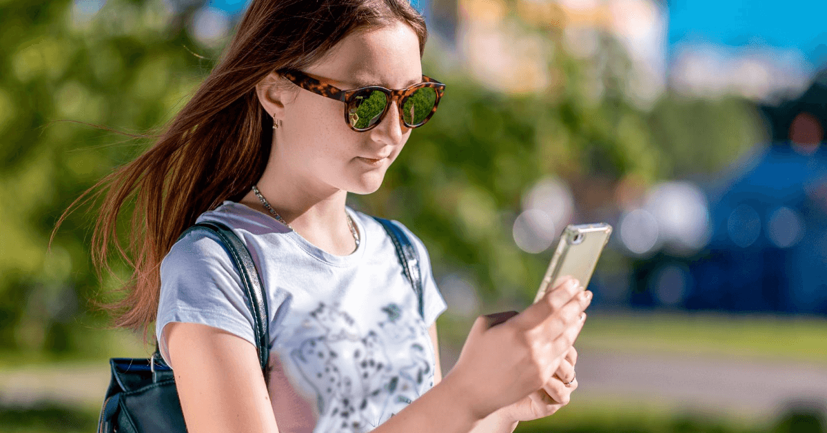 Teenage girl looking at phone screen on k-12 school campus online ordering