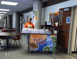 Liberal High School School Nutrition staff member setting up a Second Chance Breakfast kiosk in the hallway