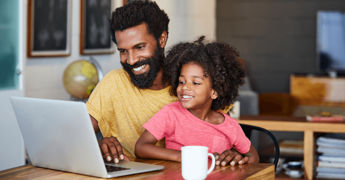 Father and child looking at laptop computer while sitting at a table online k-12 enrollment for k-12 schools