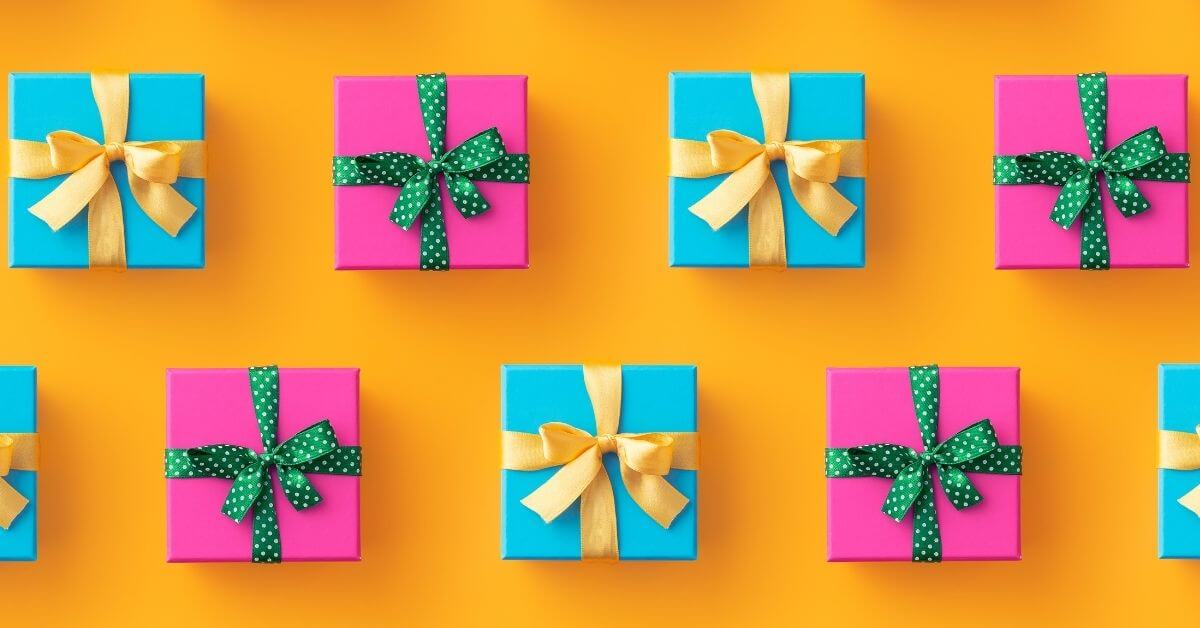 Brightly wrapped presents in offset rows on a bright orange background pink wrapping with blue ribbons teal wrapping with yellow ribbons nutrition technology greatest gift k12 schools