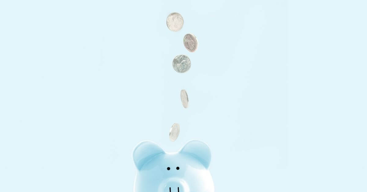 Blue piggy bank with silver coins falling into it on a blue background investing in school nutrition program