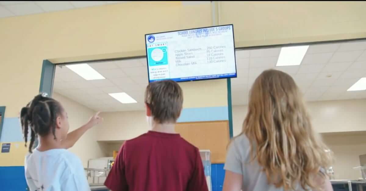 three students looking at digital menu in cafeteria