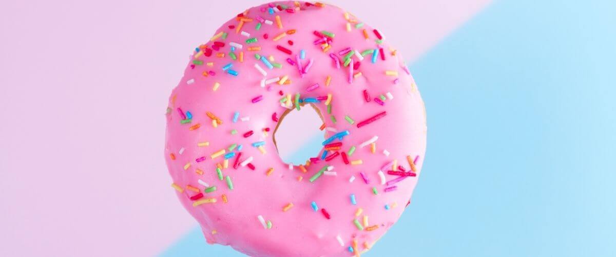 Pink and blue diagonal background with a pink-iced sprinkle donut in the middle NSBW