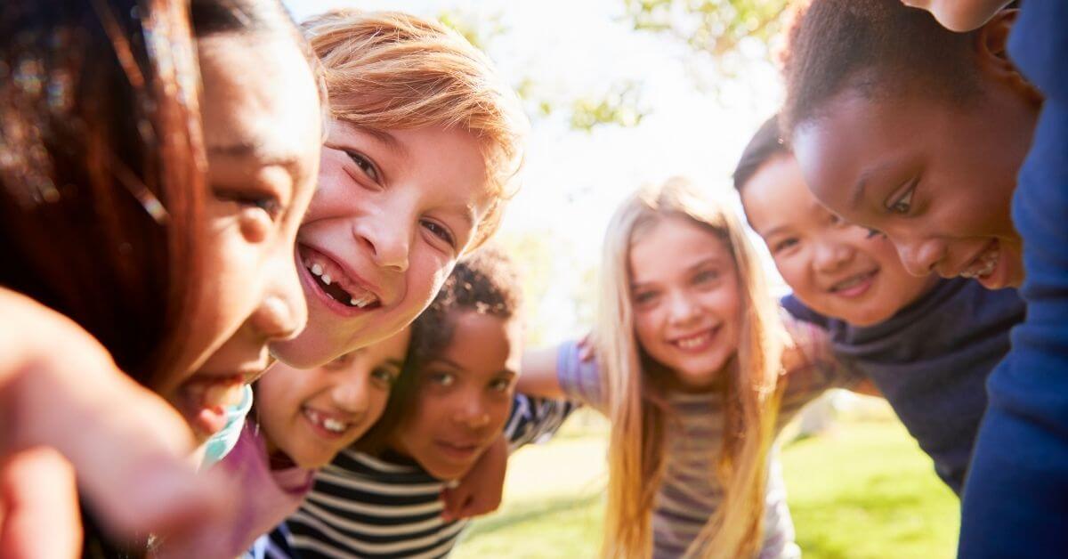 A group of children in a circle shoulder to shoulder smiling school nutrition