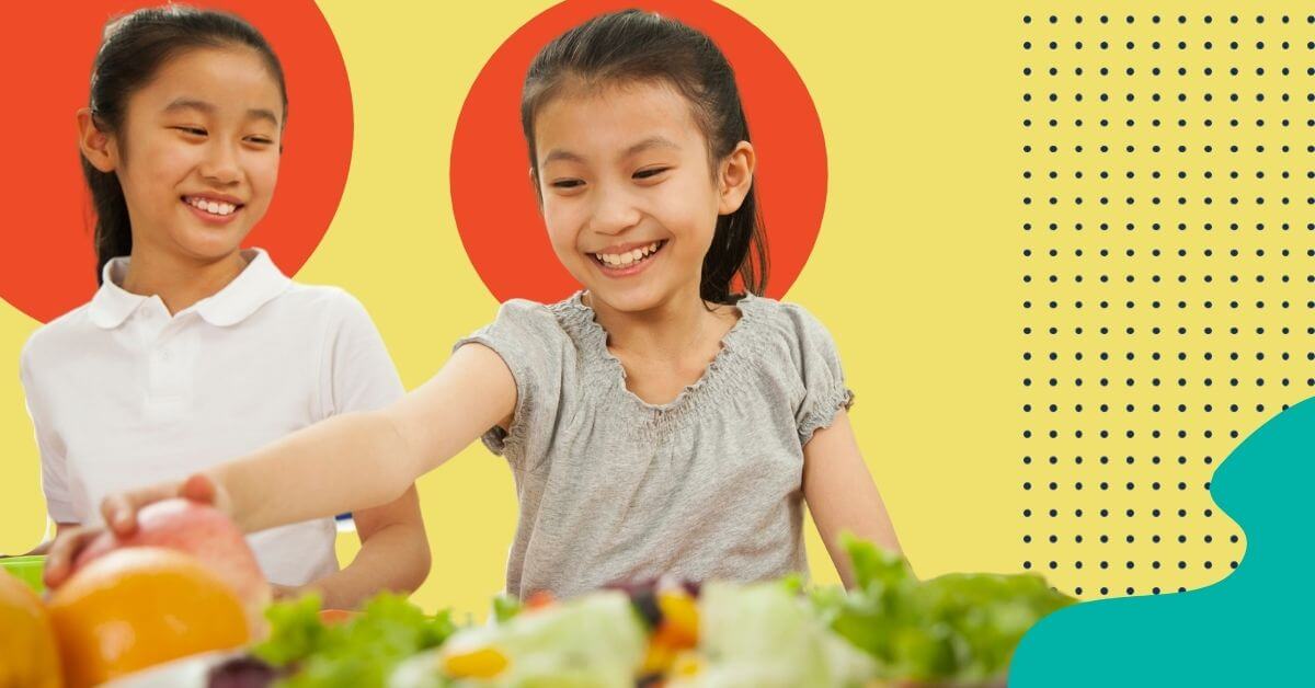 Two young and smiling girls getting lunch one is grabbing for an apple next to a salad funding risk factors for school nutrition california usda waivers
