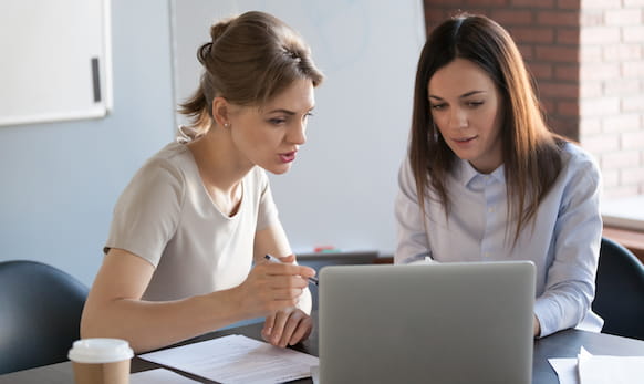 Two school district employees looking at data on a screen