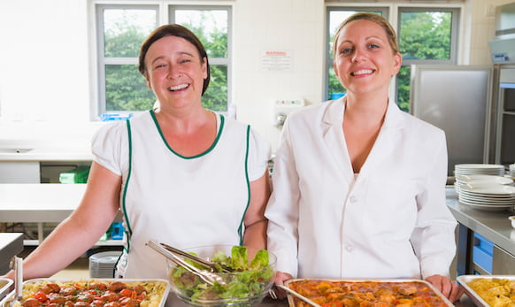 Two lunch ladies working in a school cafeteria